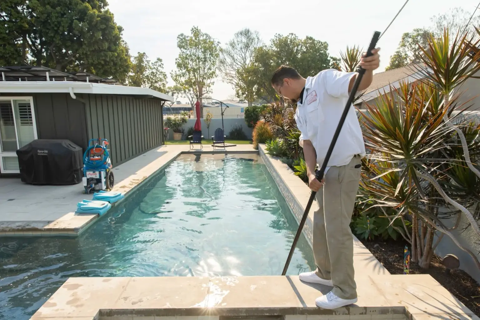 Adam's Pool and Spa technician skimming a clean residential pool in Long Beach